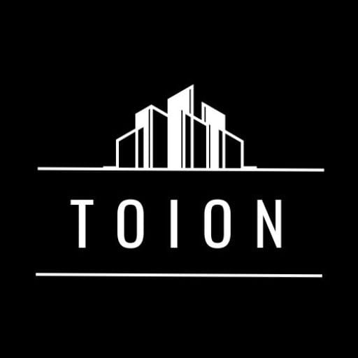 TOION-logo, jossa valkoisia rakennuksia mustalla taustalla ja teksti 'TOION'